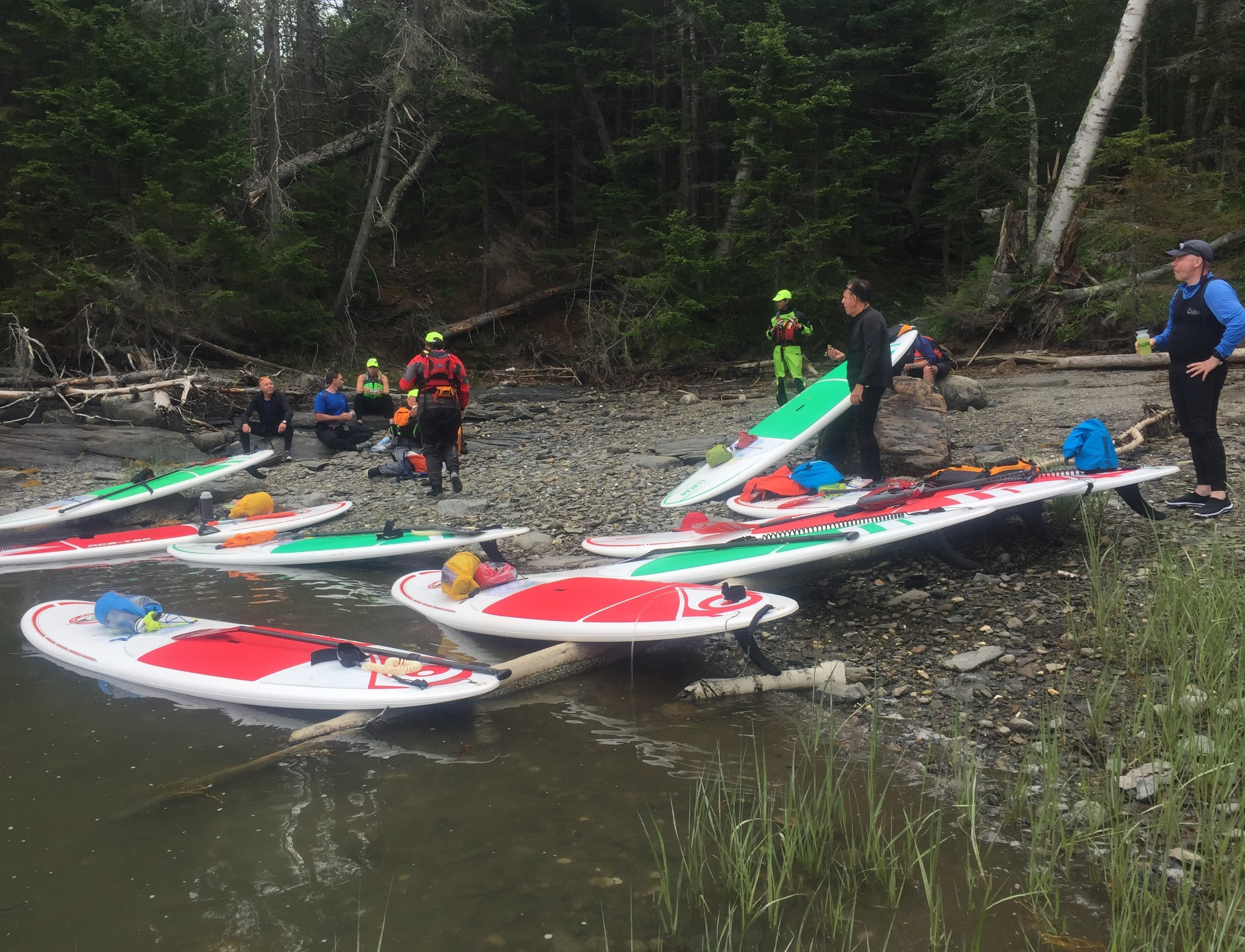 students hanging out on shore with stand-up paddleboards